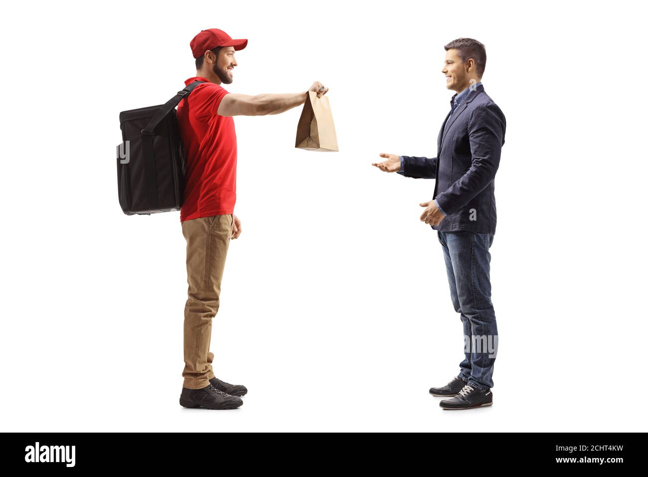 Full length profile shot of a guy delivering food bag to a smiling young man isolated on white background Stock Photo