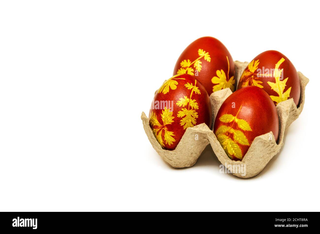 Easter eggs dyed with onion husks with a pattern of fresh leaves of plants on a white background. Creative decoration and DIY concept. Close-up Stock Photo