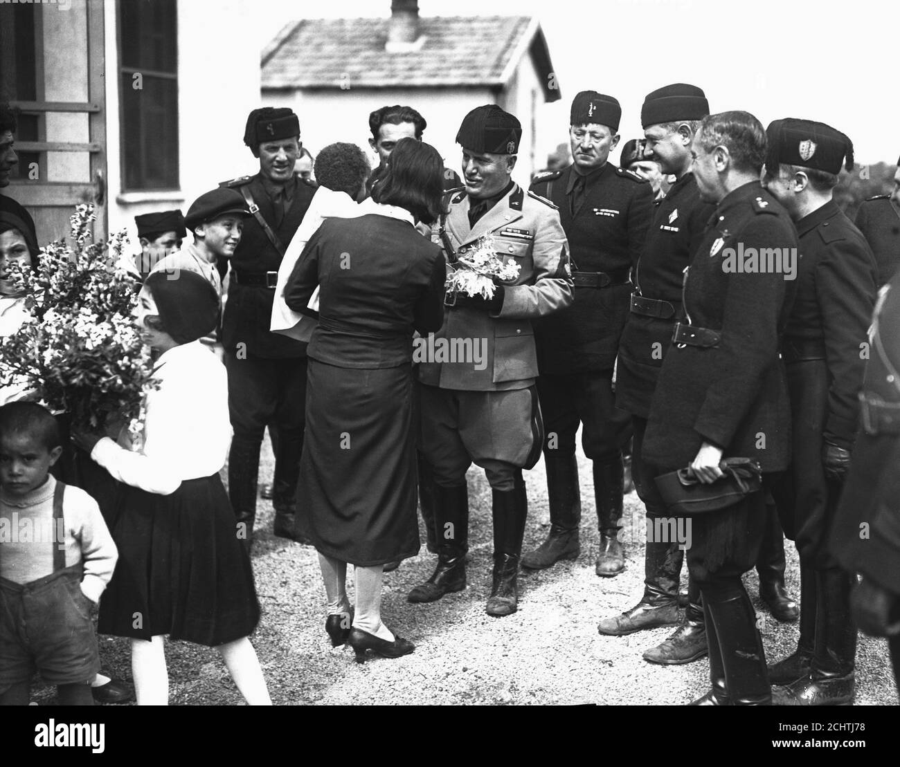 Agro Pontino campaign for Agricultural development in poor countries in Italy. Benito Mussolini given a flower gift from teachers in a children school, 1936. Stock Photo