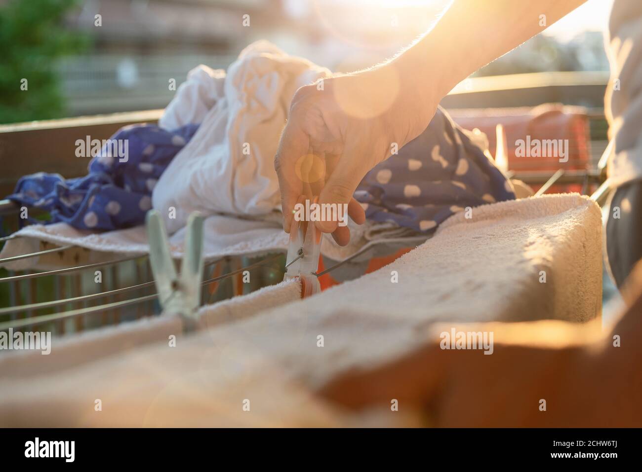 Close up hand putting a clothes pin on washed clothes on clothes dryer