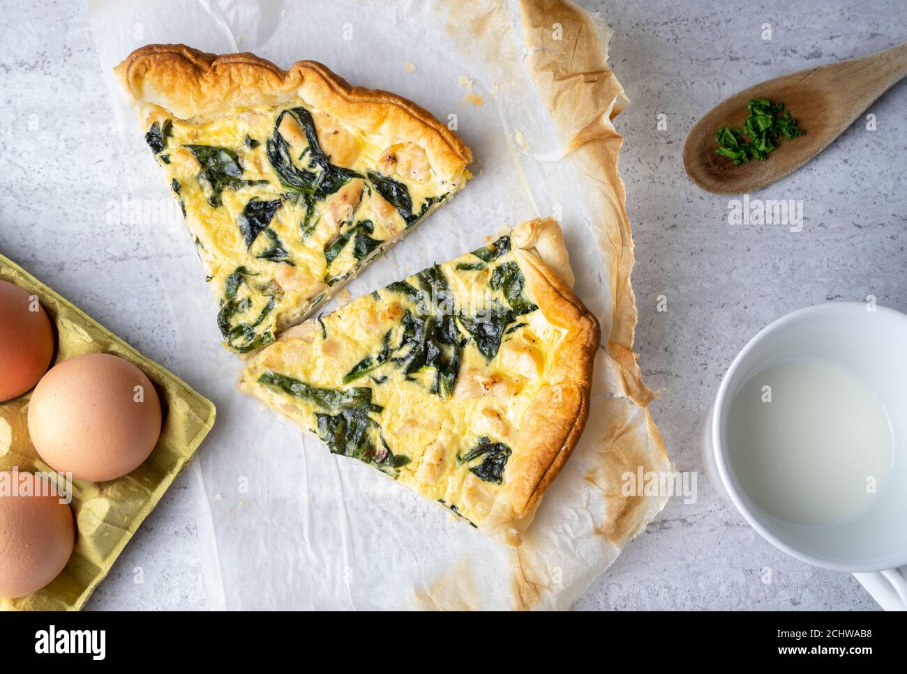 Quiche slices filled with chicken, chard with wooden spoon on soft background Stock Photo