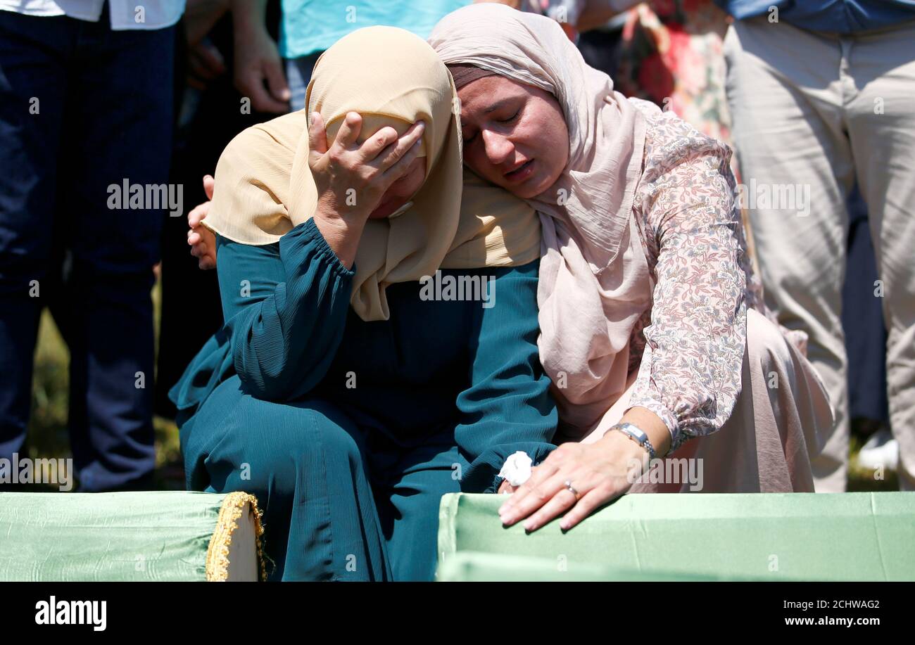 Bosnian Muslim women cry near the coffins during a mass funeral in the