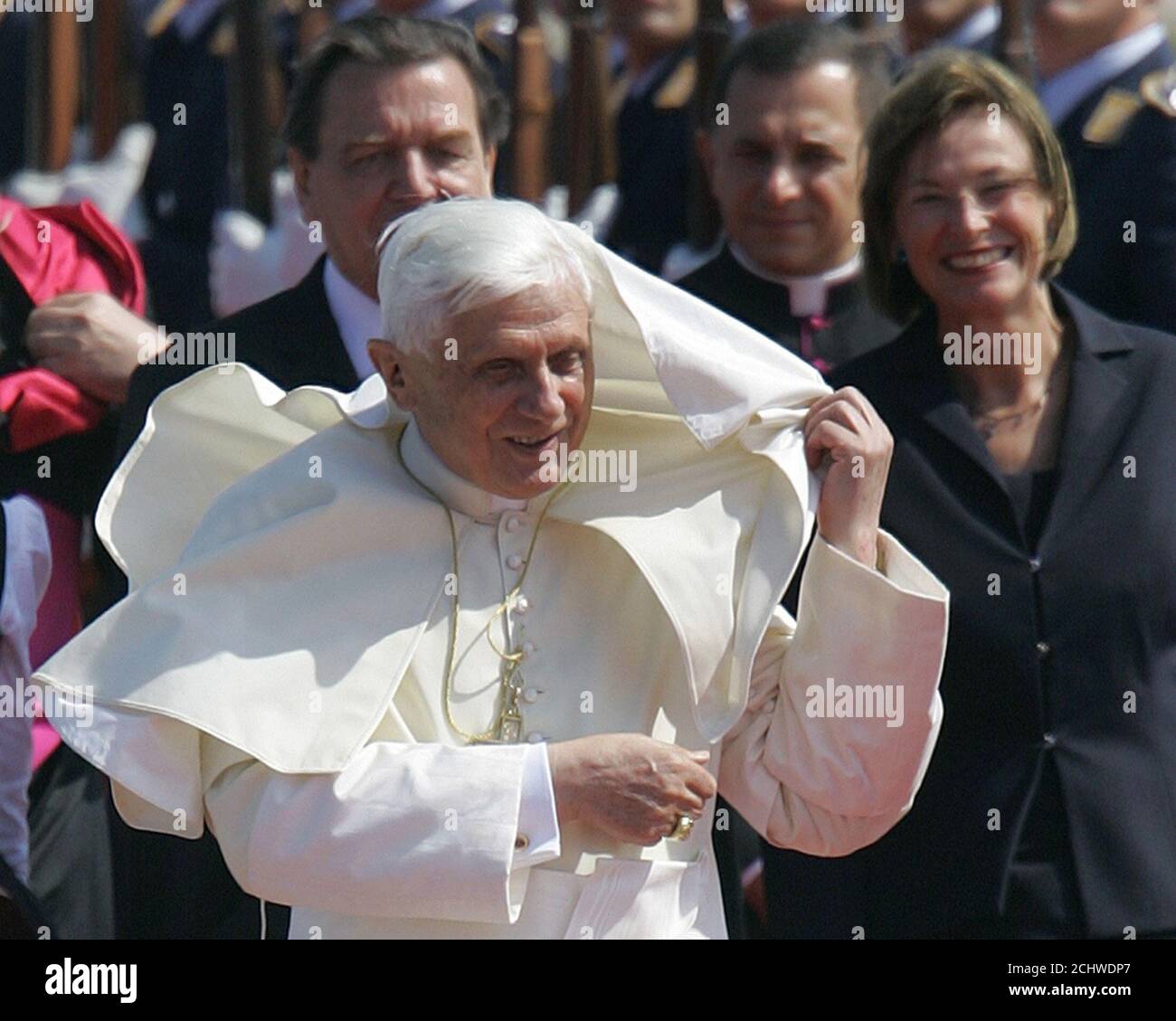 German Chancellor Gerhard Schroeder and the wife of the German President,  Eva Koehler (R) watch as Pope Benedict XVI removes his cape from his face  during his arrival at the airport in