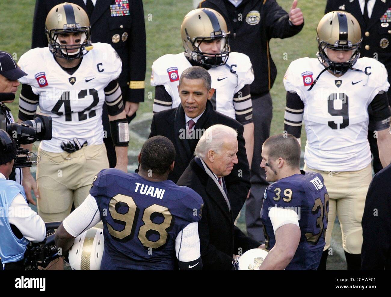 U.S. President Barack Obama (C) and Vice President Joe Biden (Center,  bottom) greet Navy team captains Jabaree Tuani (98) and Alexander Teich  (39), as well as Army team captains Andrew Rodriguez (42),