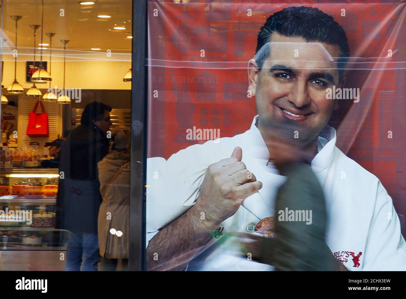 People walk by a photo of celebrity chef Buddy Valastro outside his 'Cake  Boss' cafe in New York November 13, 2014. Valastro, the star of the reality  TV show "Cake Boss" was