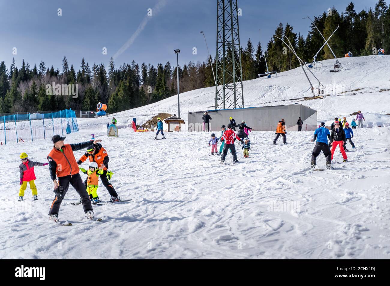 Bialka Tatrzanska, Poland, March 2019 Groups of skiers, kids and adults learning how to ski with instructors on the green ski zone in Tatra mountains Stock Photo