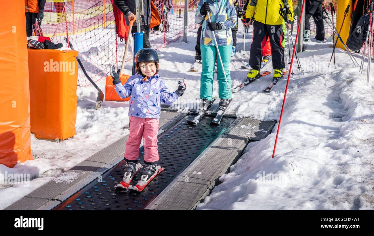Young, happy skier girl going up on conveyor lift belt to green ski zone for ski lessons, Bialka Tatrzanska, Tatry, Poland Stock Photo