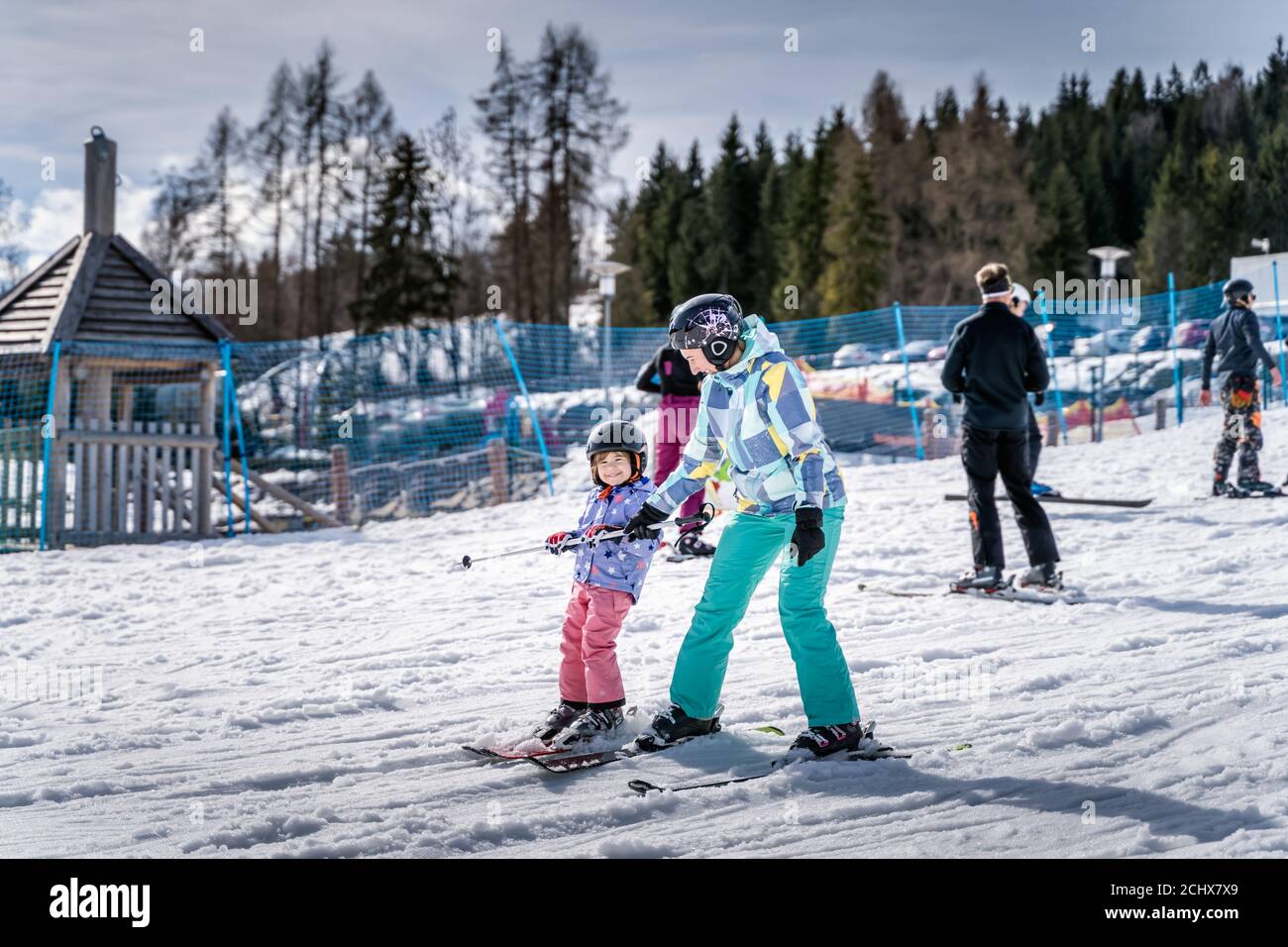 Young happy skier girl learning how to ski with her mom on the green ski zone, Bialka Tatrzanska, Tatry, Poland Stock Photo