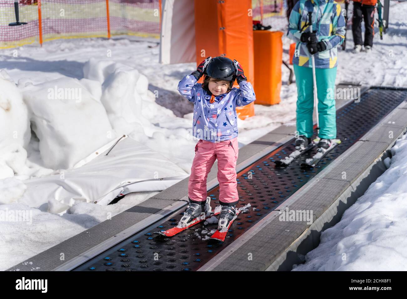 Young, happy skier girl going up on conveyor lift belt to green ski zone for ski lessons, Bialka Tatrzanska, Tatry, Poland Stock Photo