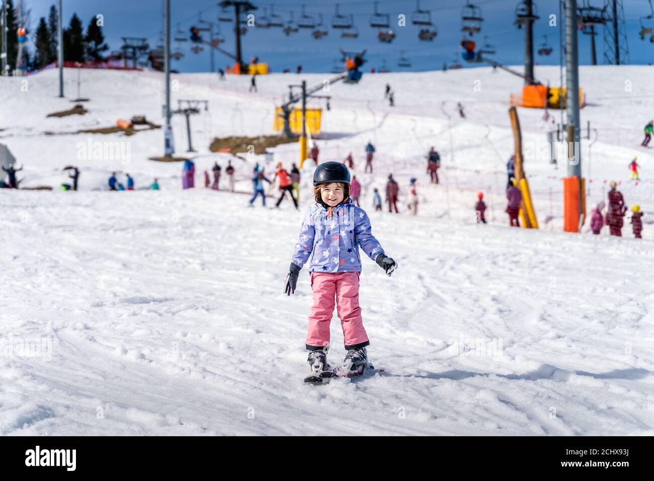 Young happy skier girl learning how to ski on the green ski zone. Young skier having fun on ski slope, Bialka Tatrzanska, Tatry, Poland Stock Photo