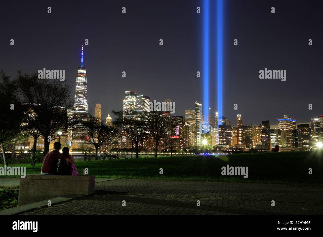 The annual "Tribute in Light" light beams project in night sky of Lower Manhattan to memorial Sept.11 terrorist attacks victims with people viewing it in Liberty State Park in foreground.New Jersey.USA Stock Photo