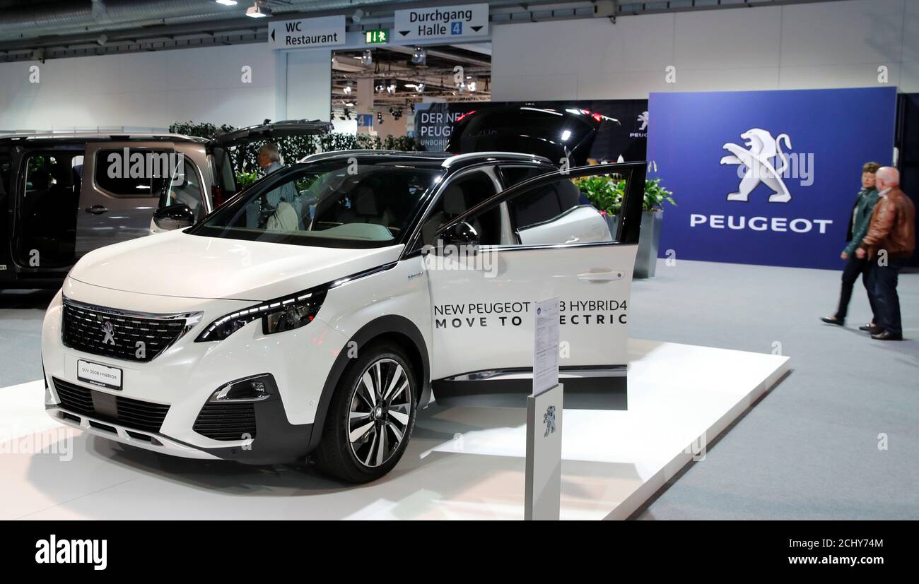 The logo of French car manufacturer Peugeot is seen behind a SUV 3008  Hybrid4 car displayed