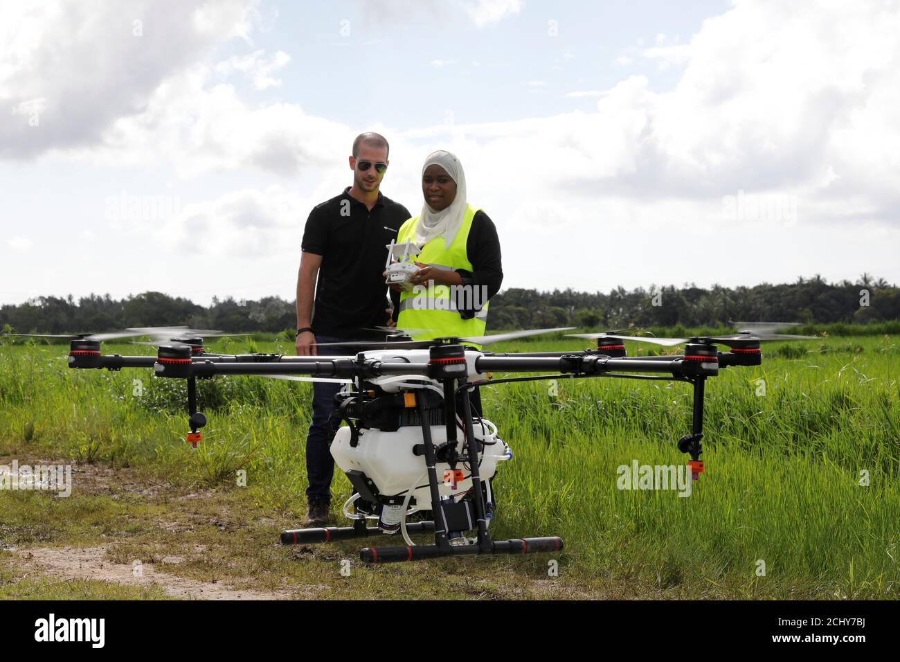 Tanzanian drone pilot Khadijah Abdulla Ali (R) flies a customized DJI Agras  MG-1S drone next to DJI's Enterprise Product Manager Eduardo Rodriguez  during a training flight as part of a test in