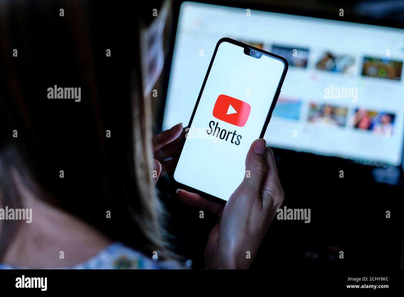 : Youtube Shorts app logo seen on the smartphone which hold by young girl. It is a new short looping video  app, competitor to TikTok, Bytes and Reels Stock Photo