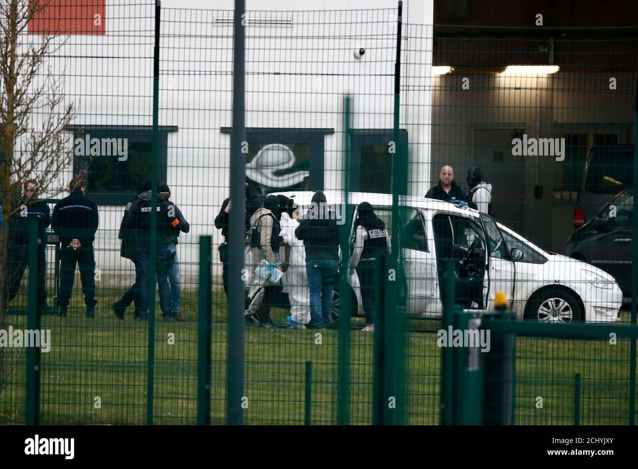 Masked special forces police escort a woman into a waiting van outside the  prison where an inmate in one of France's most secure prisons stabbed two  guards with a knife in Conde-sur-Sarthe,