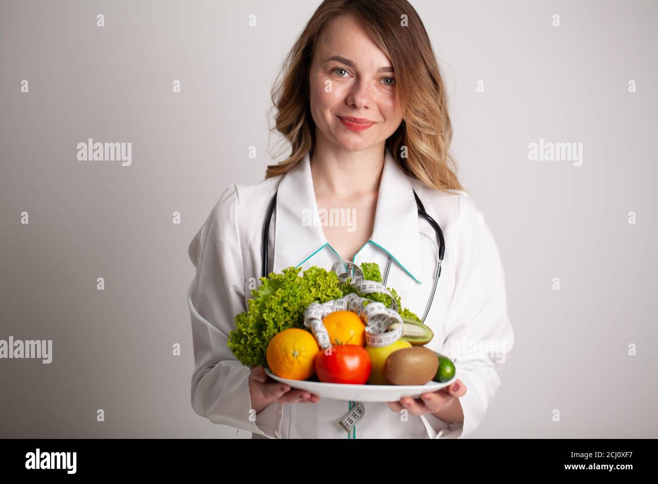 Beautiful young female nutritionist with fresh vegetables and fruits Stock Photo