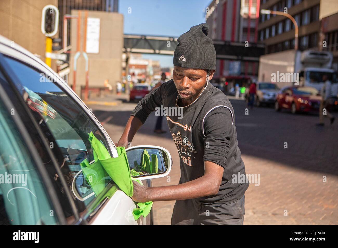 African young male washing a car in city centre of Johannesburg, South
