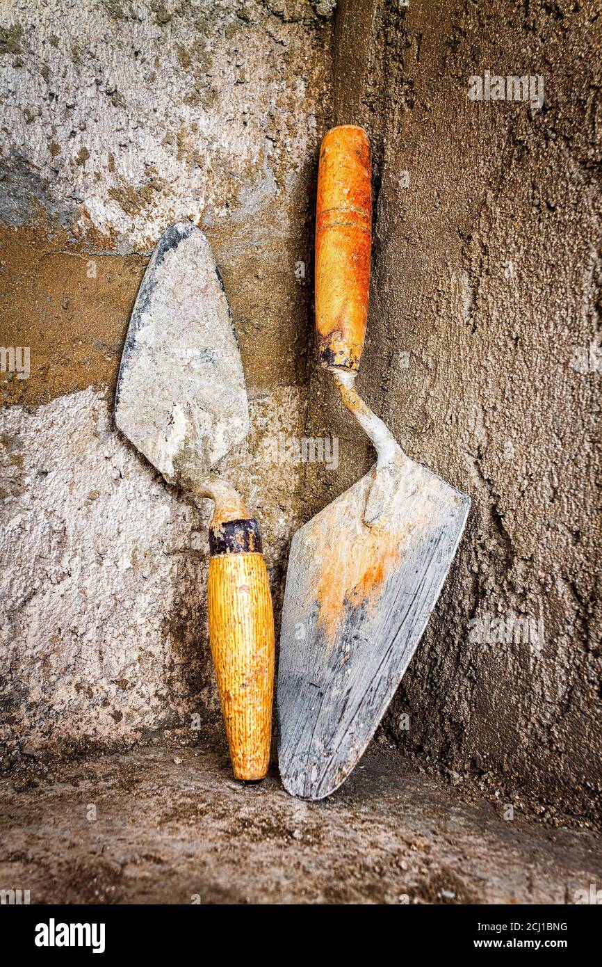 Dirty trowels leaning on a rough concrete wall Stock Photo Alamy