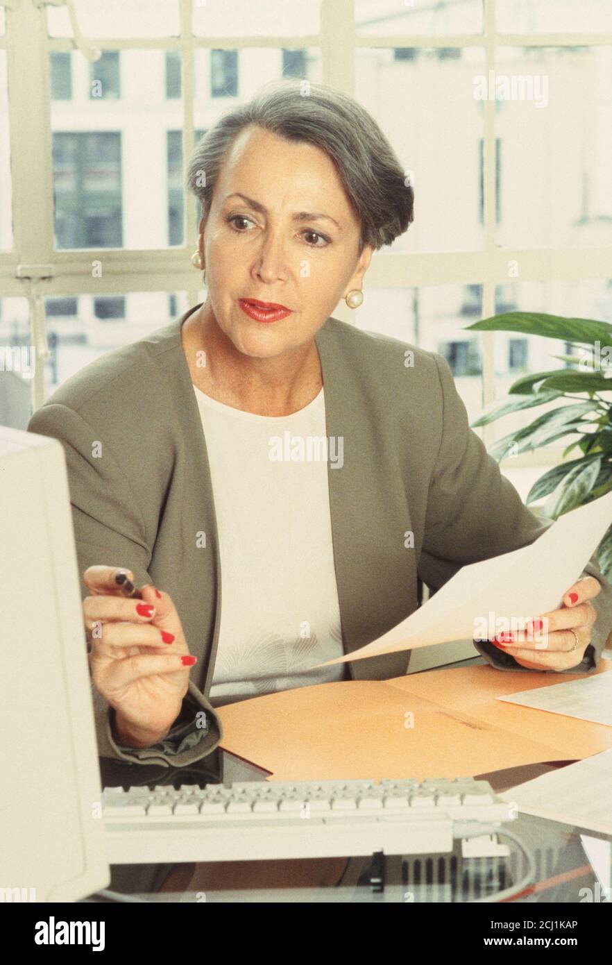 1990s Middle aged Businesswoman Working at her Desk, USA Stock Photo