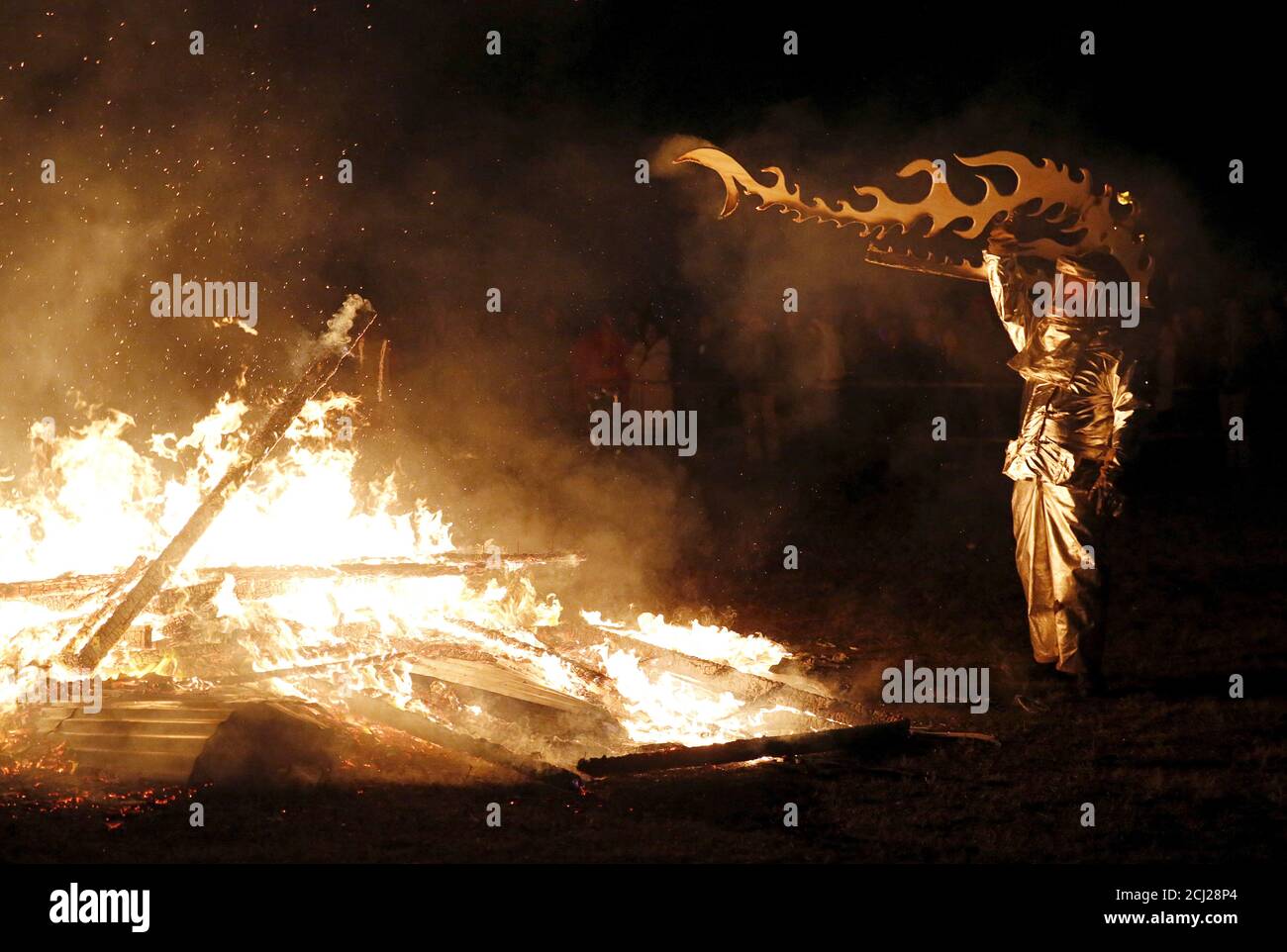 A fire safety worker tosses a piece of an interactive art installation by artist Michael Verdon called the “Temple of Essence” dedicated to 'victims of the war on drugs' back into the fire as the installation is burned on the U.S. National Mall in Washington November 22, 2015. People were encouraged to write personal messages on the temple walls and leave mementos behind inside the interactive art piece, which was the centerpiece of a 48-hour vigil called 'Catharsis on the Mall: A Vigil for Healing the Drug War.'     REUTERS/Jim Bourg Stock Photo