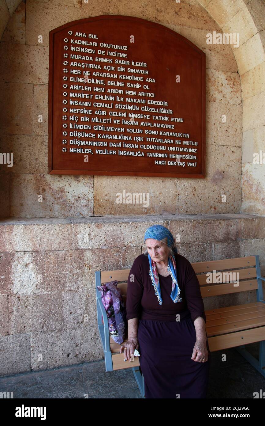 HACI BEKTAS, TURKEY - AUGUST 25: Old woman visiting at famous mosque of Haci Bektas Veli and behind writes the rules of humanity on August 25, 2013 in Nevsehir, Turkey. Stock Photo