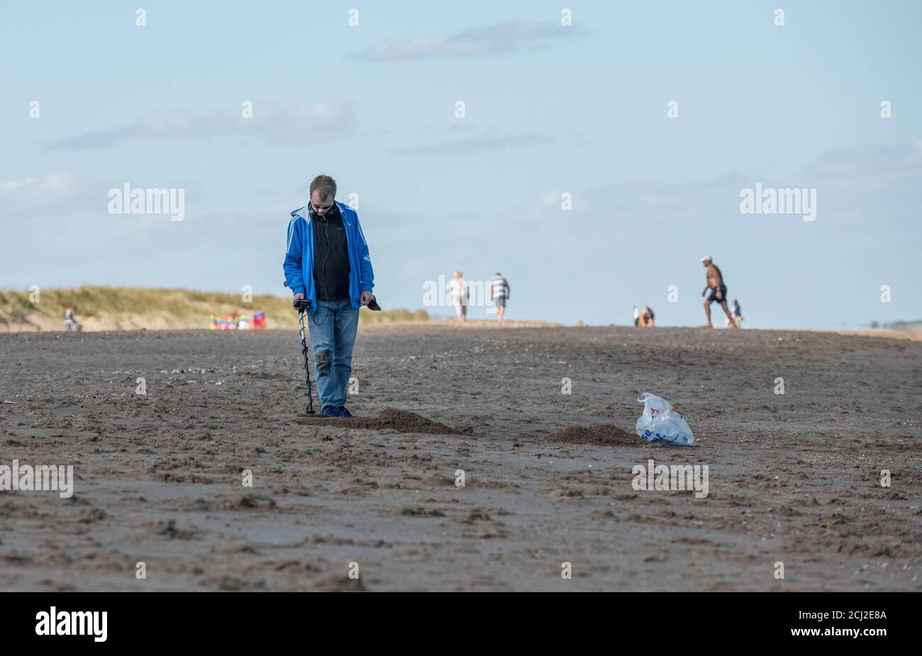 Detectorist with metal detector operating on the beach at Anderby Creek, Lincolnshire, England