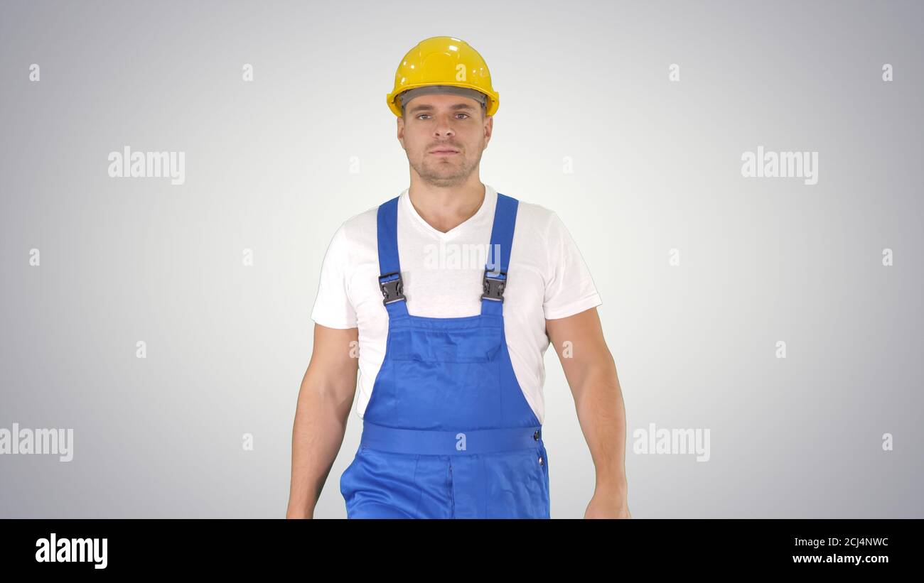 Walking worker in yellow helmet on gradient background. Stock Photo