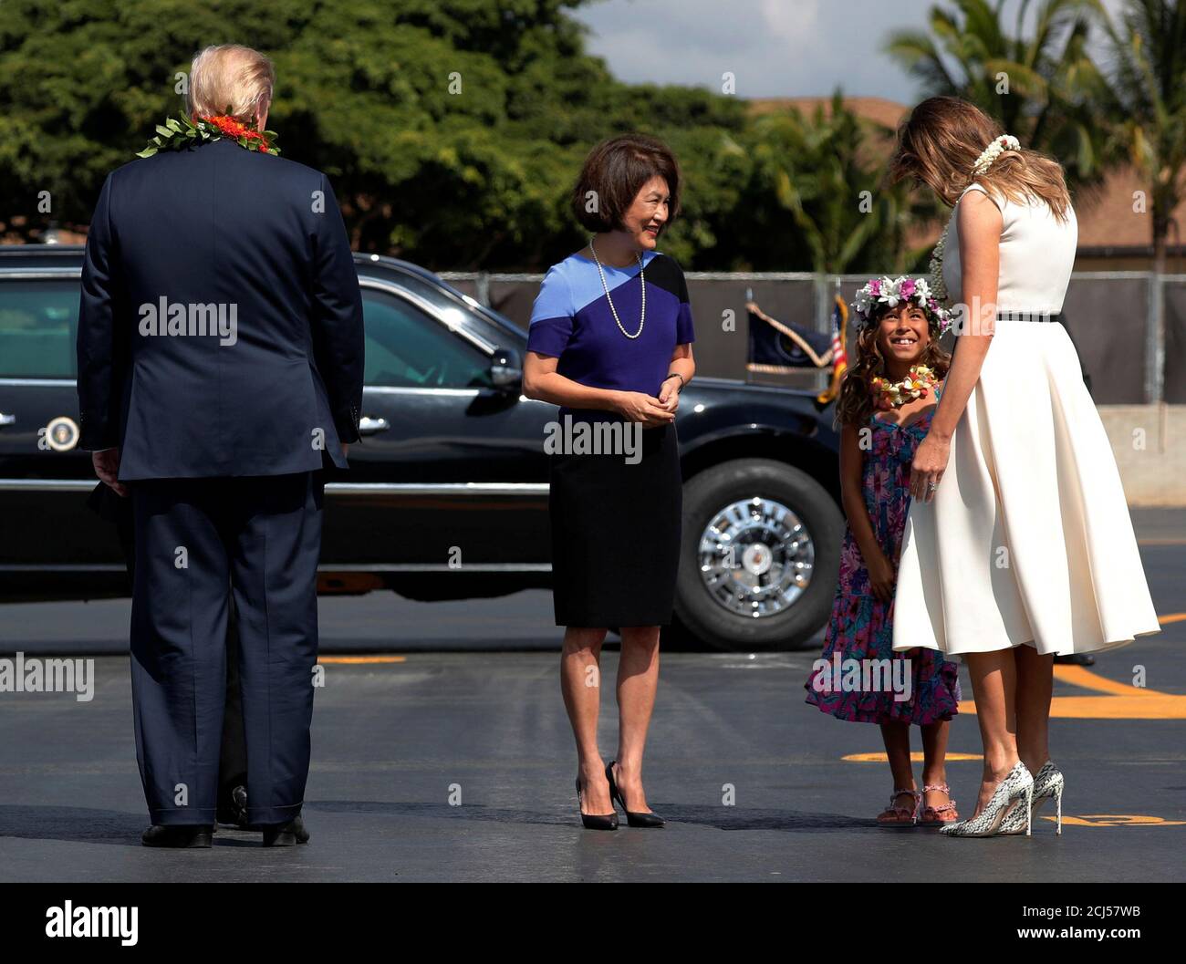 Dawn Ige (C), the wife of the governor Hawaii, looks on as Mikayla Webb  (2nd R) presents flower leis to U.S. President Donald Trump and first lady  Melania Trump as they arrive