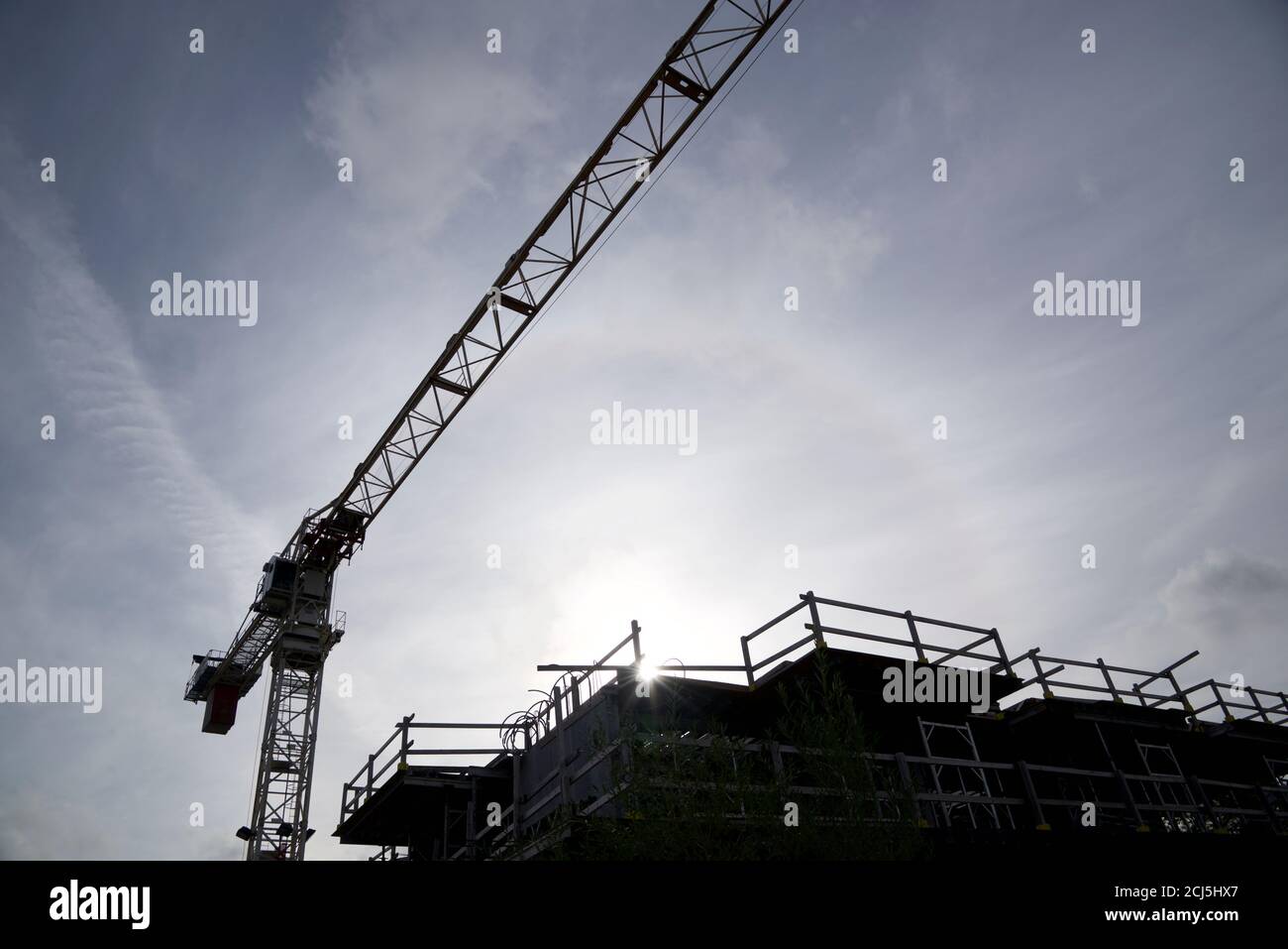 Silhouette of the construction crane in a construction site with lens flare. Stock Photo