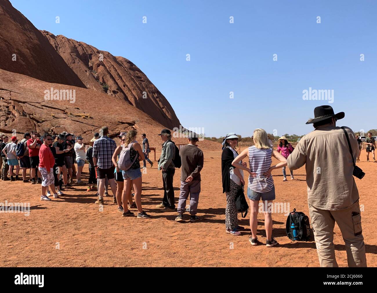 People line up to climb Uluru, formerly known as Ayers Rock, the day before a permanent ban on climbing the monolith takes effect following a decades-long fight by indigenous people to close the trek, near Yulara, Australia, October 25, 2019.  REUTERS/Stefica Bikes Stock Photo