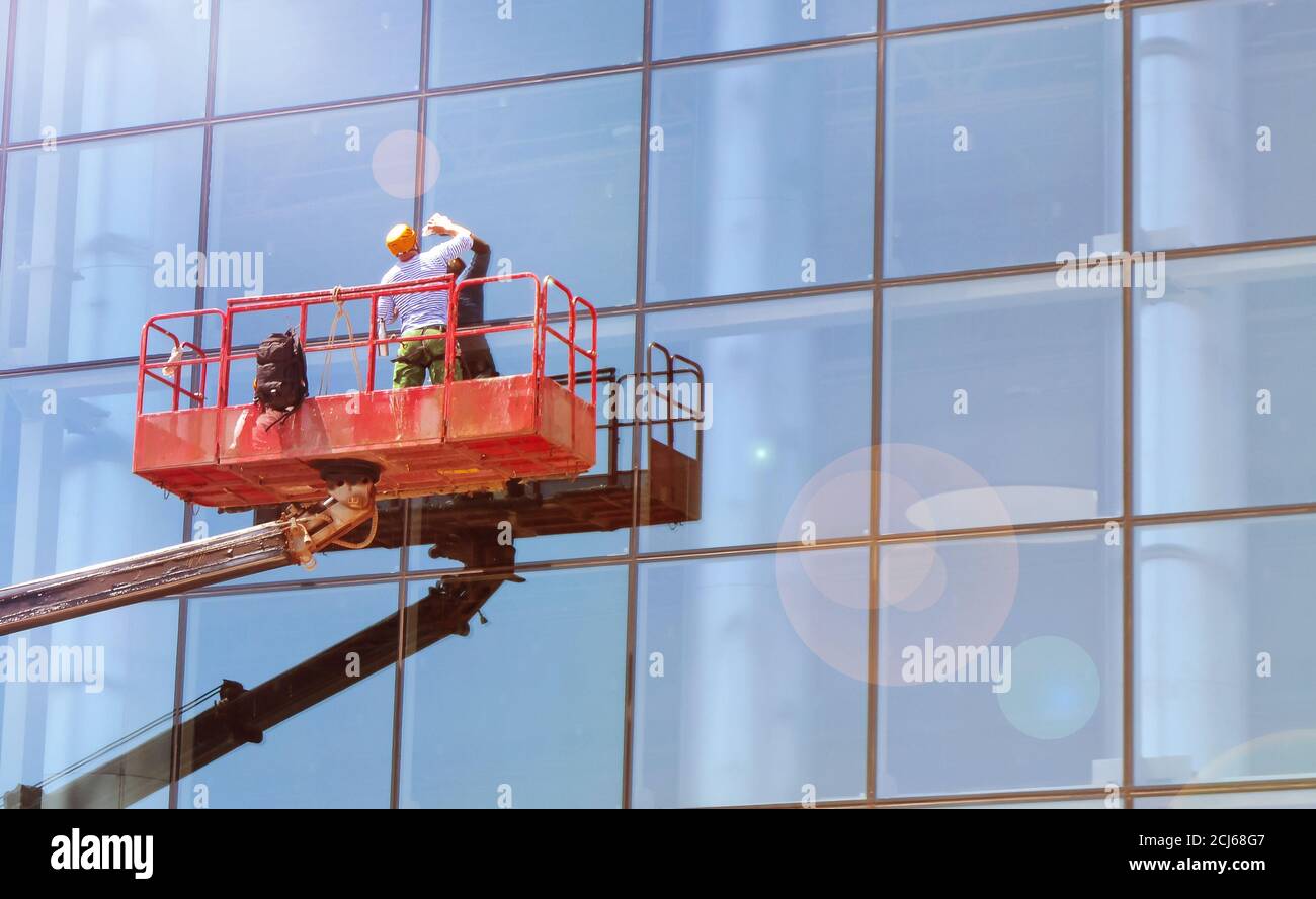 Working window cleaner on a telescopic platform washes the Windows of a