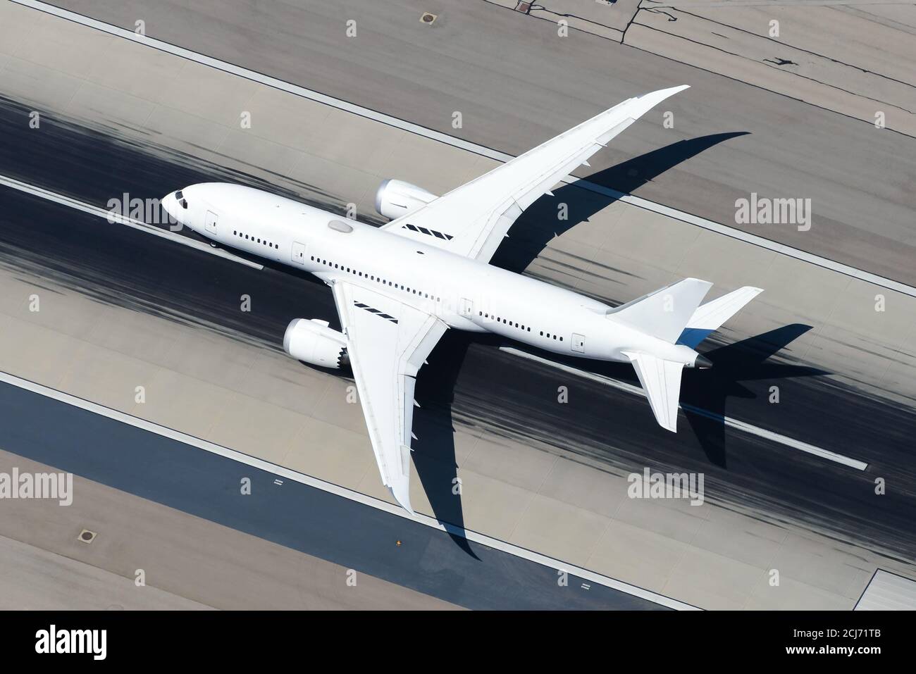 Unidentified aircraft departing international airport runway. White untitled airplane aerial view. Large widebody plane. Stock Photo