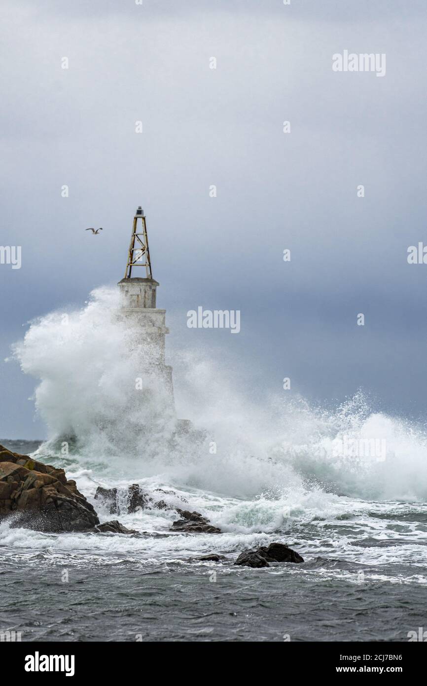Tall lighthouse in the stormy ocean under dark storm clouds Stock Photo ...