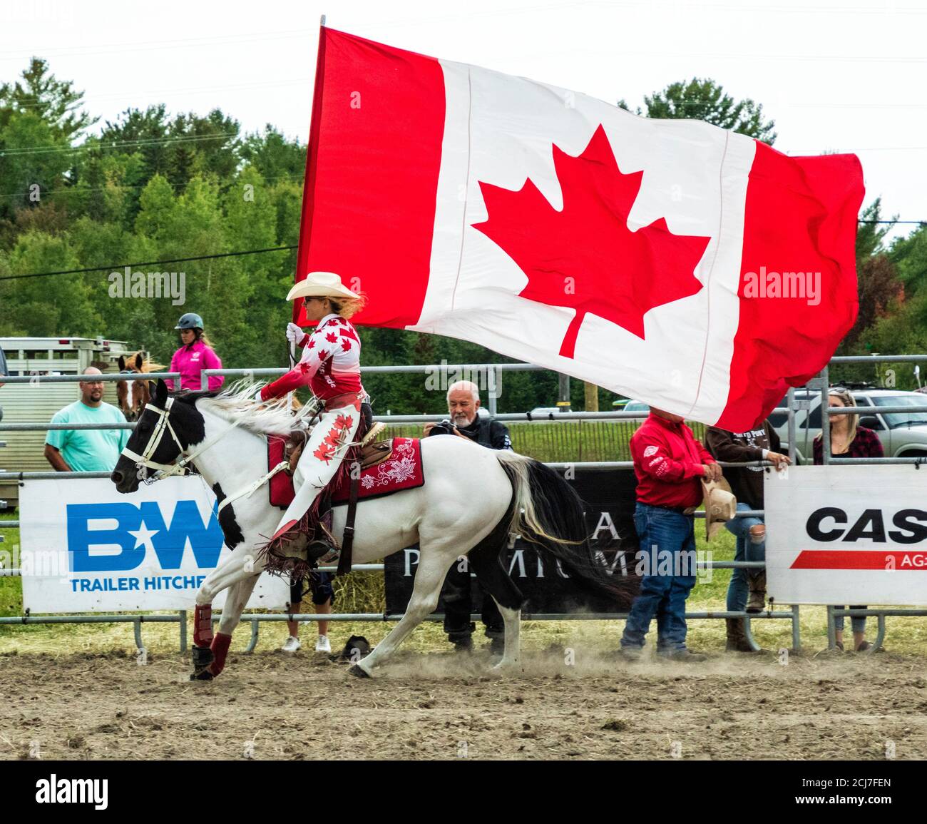 Rider on horseback with Canada flag at rodeo grounds, International