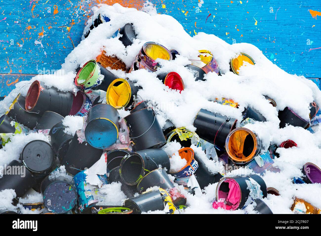 Pile of empty discarded paint cans showing colours under snow. Stock Photo