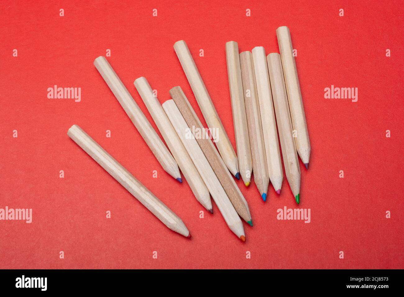 Colored pencils on red background. Many different colored pencils. Stock Photo