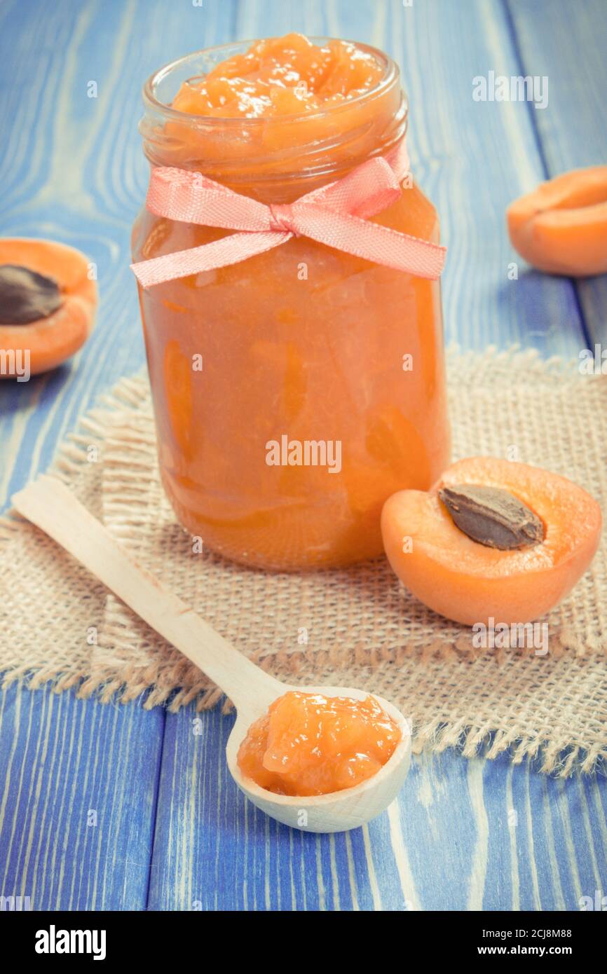 Vintage photo, Fresh homemade apricot marmalade and ripe fruits on blue boards, concept of healthy sweet dessert Stock Photo