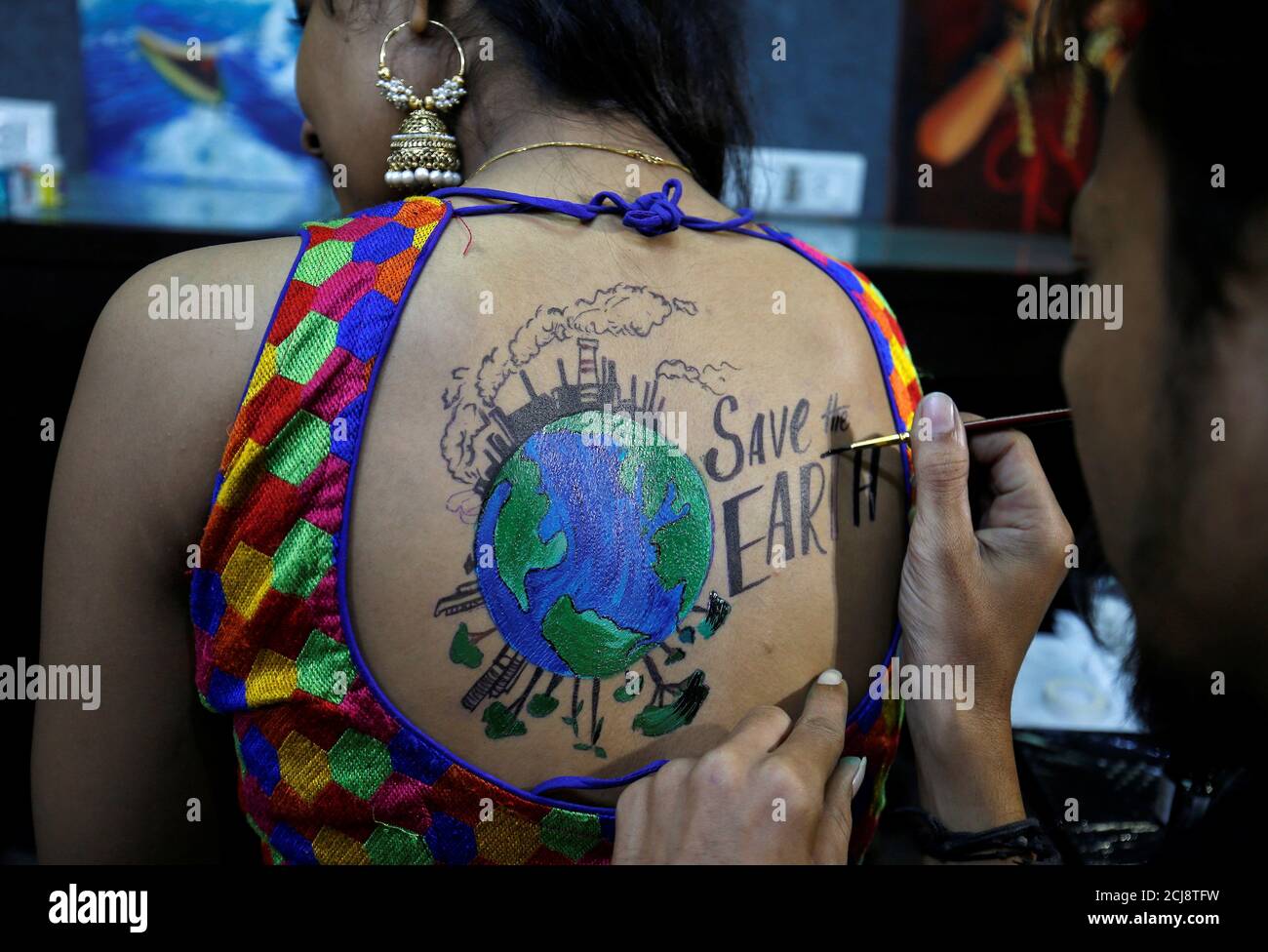 An artist applies final touches to a body paint tattoo sketched on the back  of a woman in preparations for the upcoming Navratri, a festival when  devotees worship the Hindu goddess Durga
