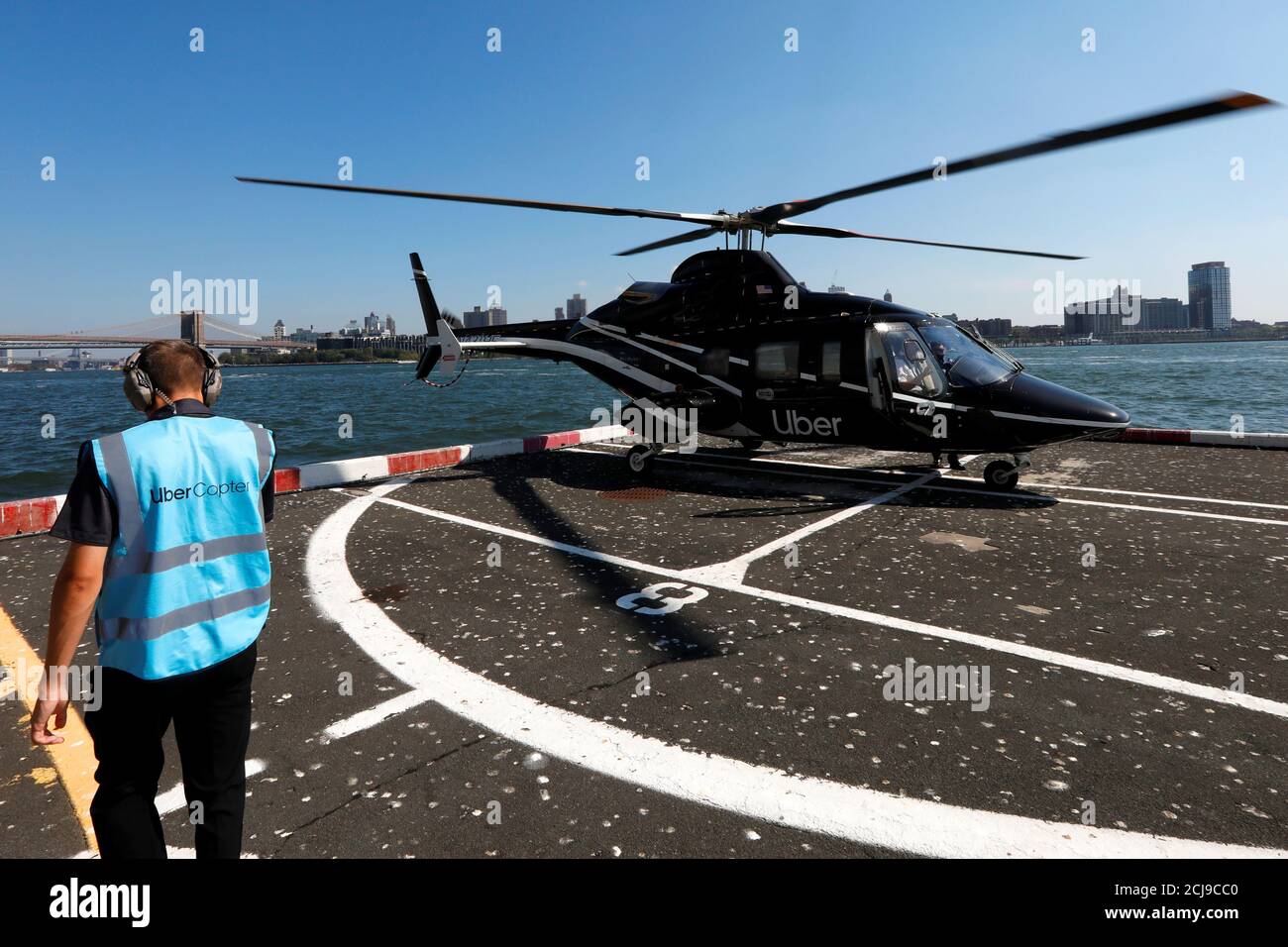 A worker walks media members to a waiting helicopter operated by 