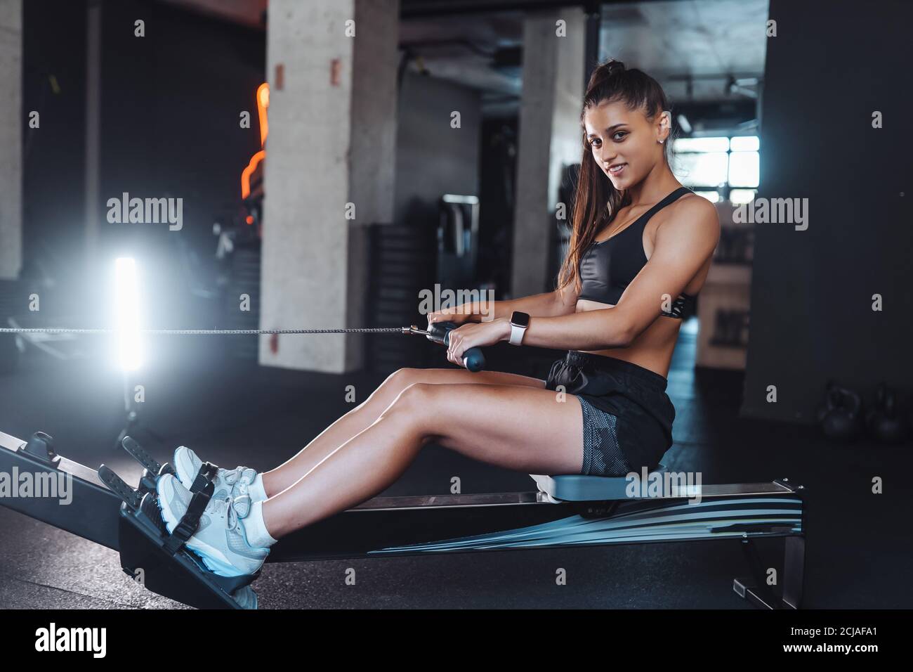 Young woman training and pulling weights in seated cable row machine Stock Photo Alamy
