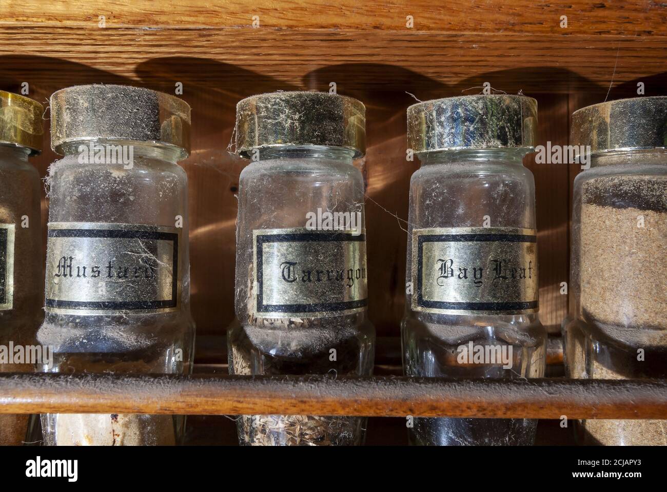 Closeup of old and unused condiments' bottles on a dusty wooden rack in an abandoned house Stock Photo