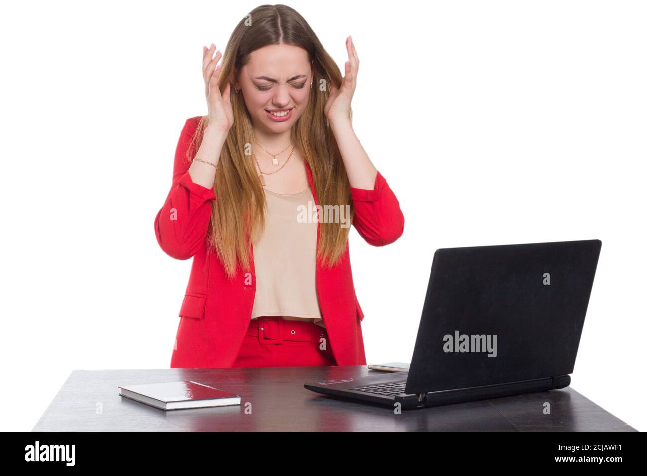 A young business office woman in a red suit a background isolated in white, holding a laptop, and talking on a smartphone Stock Photo
