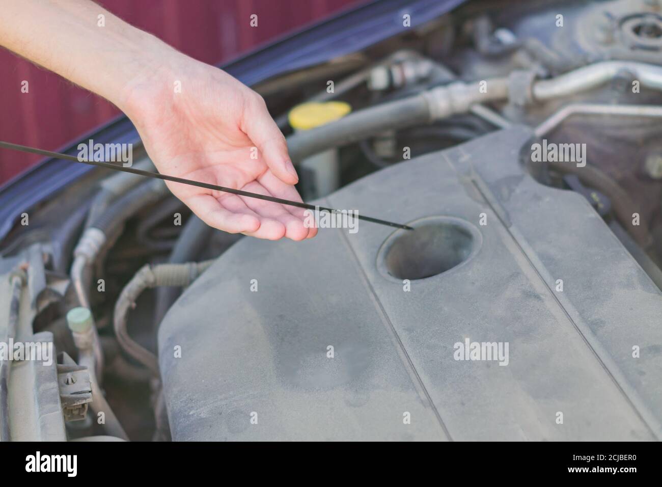 Mechanic checking and fixing an oil filler cap of a broken car on the