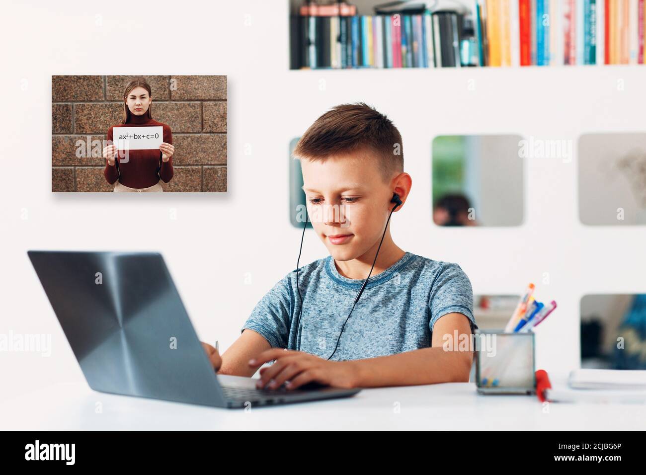 Young boy in headset sitting at table with laptop and preparing to school by teacher with white poster and quadratic equation on computer screen Stock Photo