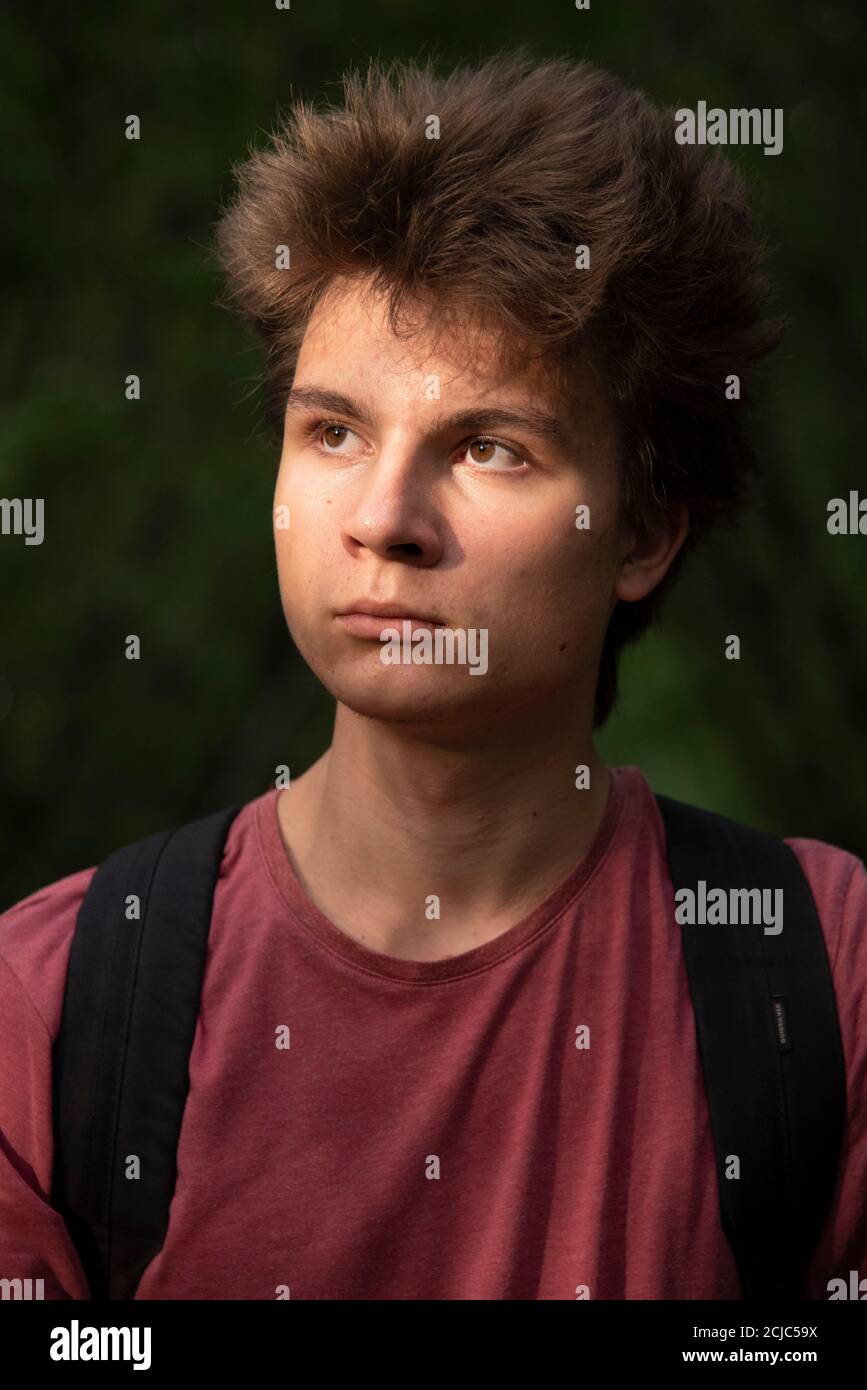 Portrait of a young teenager 17 years old in a red t-shirt with thick ...