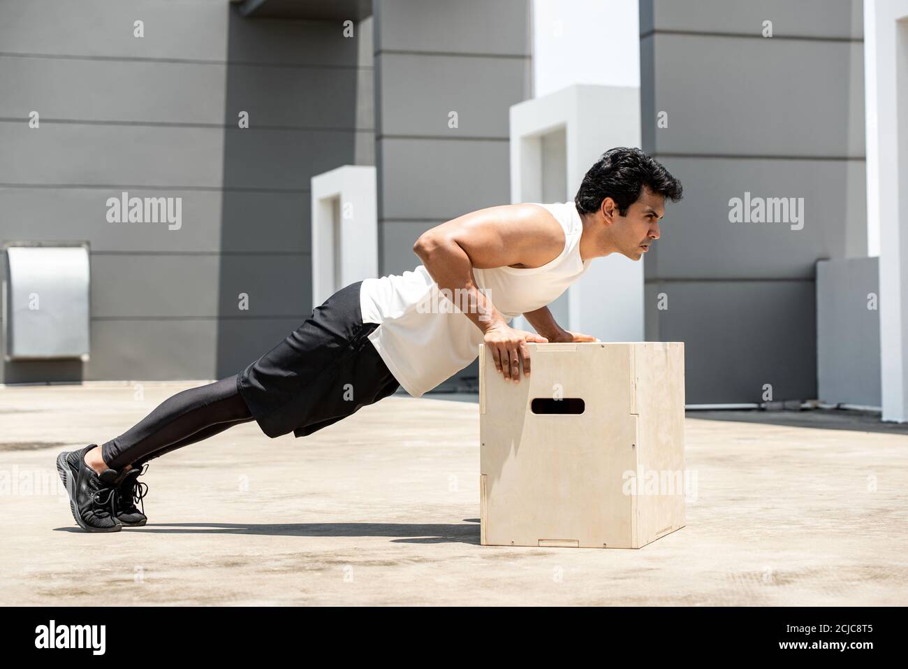 Handsome Indian sports man doing push up exercise outdoors on building rooftop, home workout in the open air concept Stock Photo