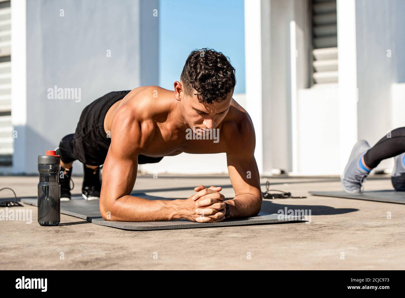 Muscular sports man doing plank exercise in the open air on building rooftop Stock Photo