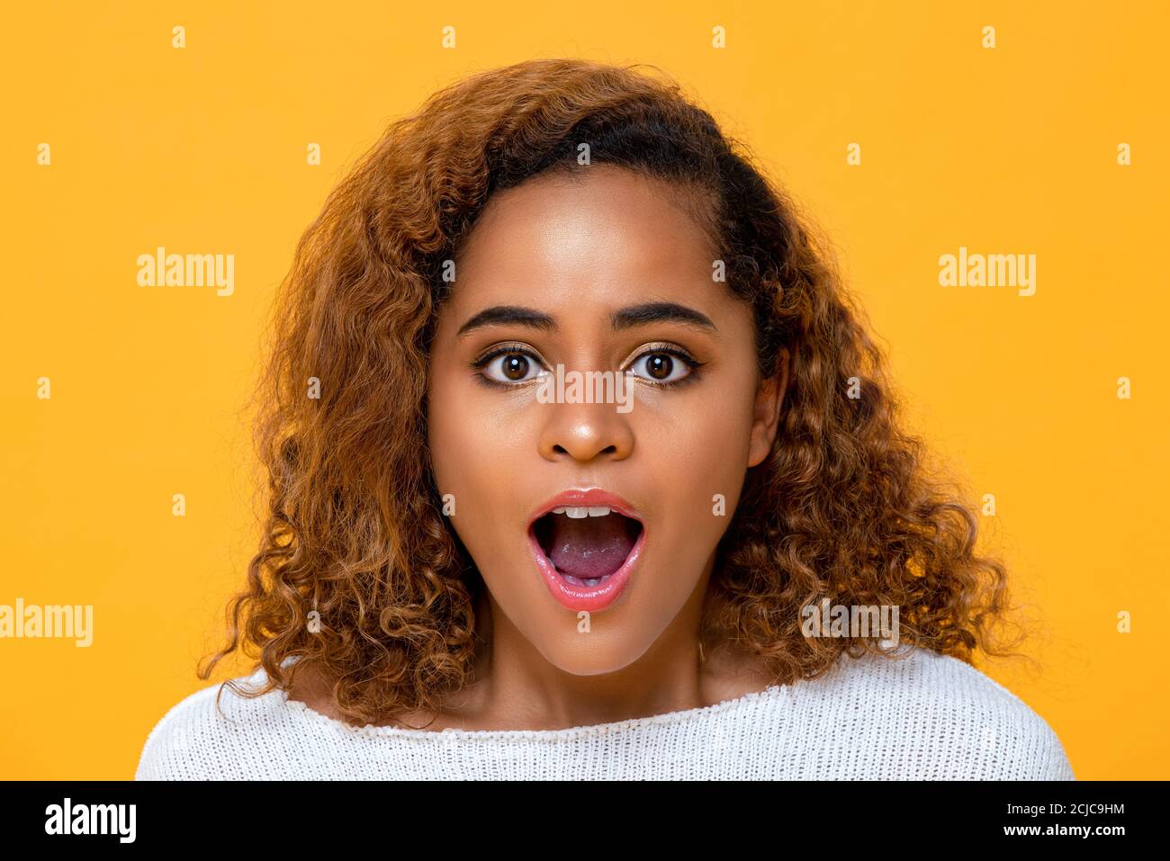 Yougn African American woman being surprised and gasping on yellow isolated background Stock Photo