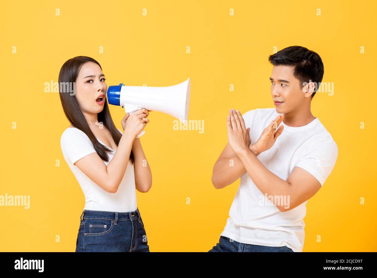 Portrait of Asian couple reacting to negative announcement in isolated studio yellow backgound Stock Photo