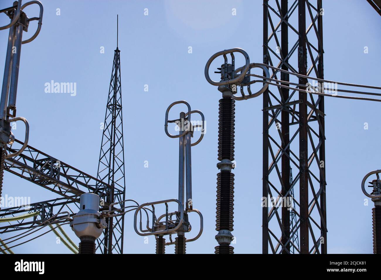 Electric power station. Transformer station (electrical substation). Silhouette of pylons, girders, insulators and wires on blue sky. Stock Photo
